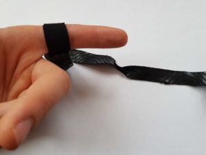 Schwarzes Tape wird zur Hälfte um einen Finger gewickelt